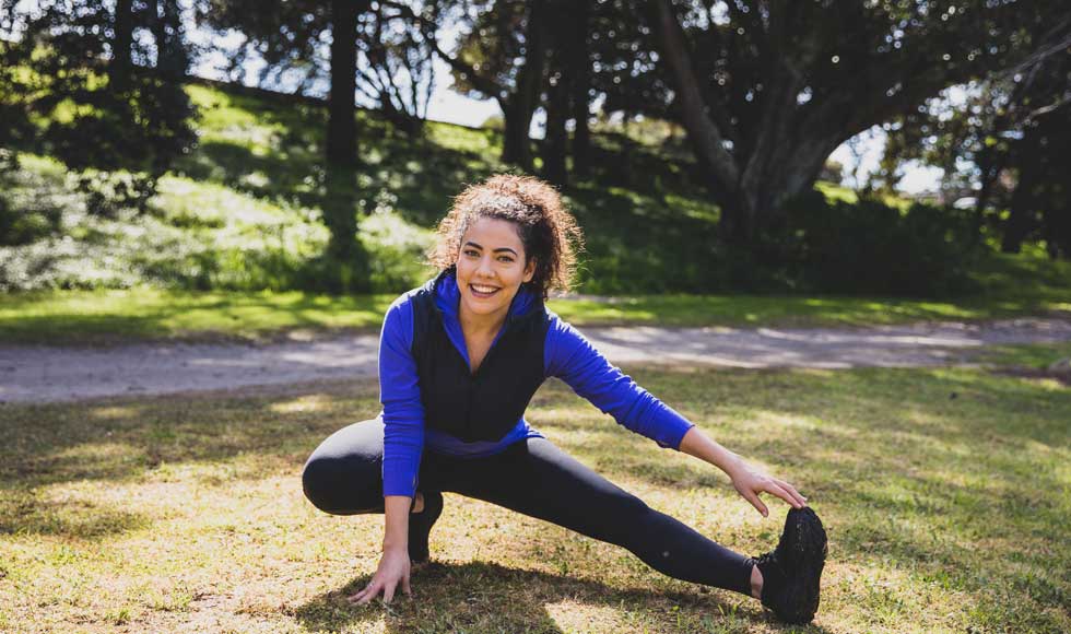 Ash London stretching in the park