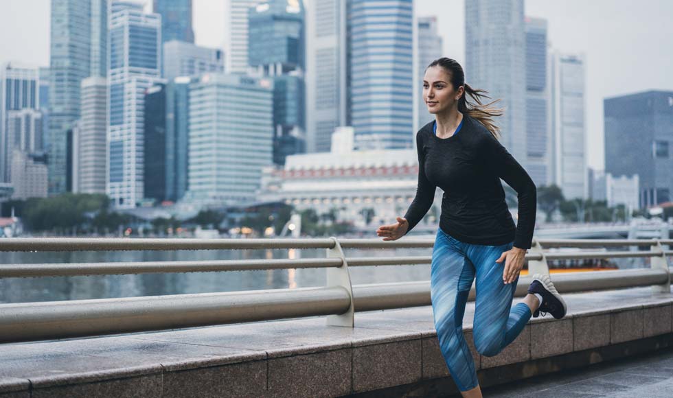 Woman running across a footbridge in the city in Singapore