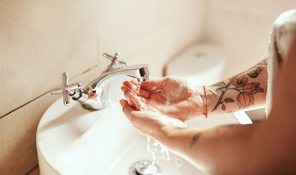 Woman washing her hands at the bathroom sink with soap and water