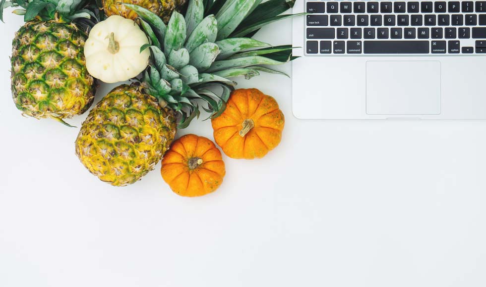 Pineapple, pumpkin and a mac book laptop on a white background