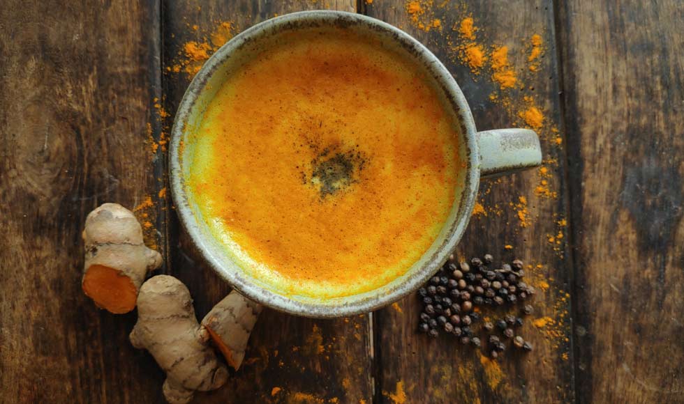 Flat lay shot of a turmeric latte on a wooden table