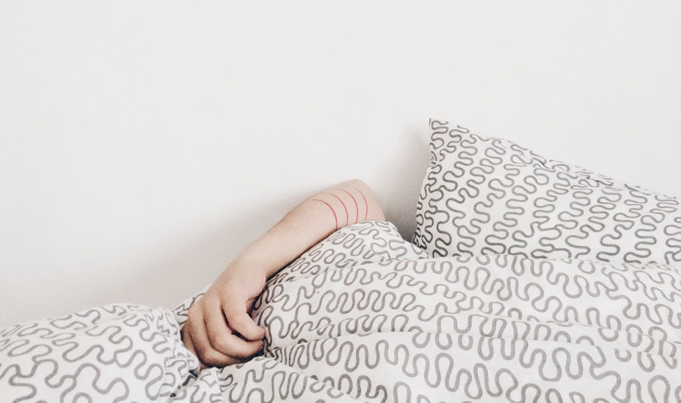 Person sleeping under a white and black bed cover