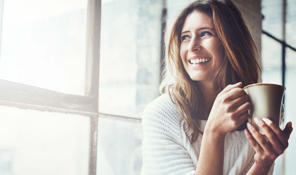 Smiling woman looking out a sunlit window